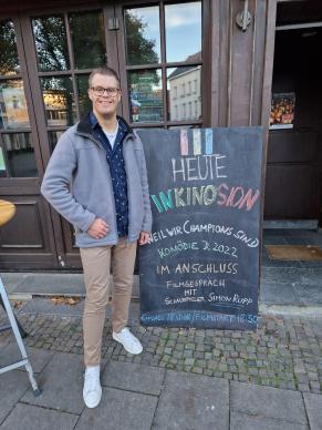 Simon Rupp vor der Königsburg, neben dem Werbeschild für InKinosion